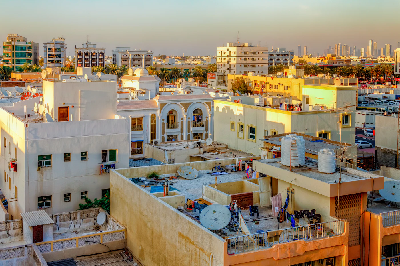 أسطح مبانٍ سكنية متقاربة في مدينة خليجية تعلوها خزانات مياه علوية وأطباق استقبال
